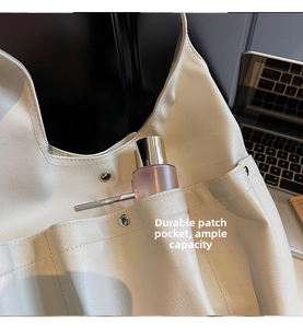 Detail shot of a beige tote bag featuring multiple external pockets and metal clasp