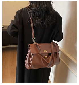 Detailed side view of dark brown leather tote bag with accordion pleats and gold lock