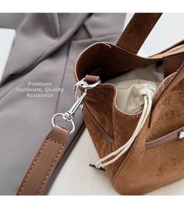 Detail of brown suede bucket bag featuring silver metal swivel hooks and drawstring liner