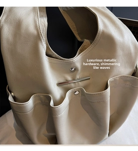 Close-up of cream white faux leather tote bag showing textured pockets and silver hardware