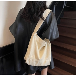 Vue détaillée du sac fourre-tout en toile crème avec large bandoulière sur le mannequin