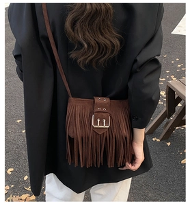 Detail of dark brown suede crossbody bag with long tassels and golden metal buckle