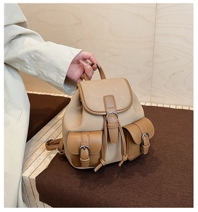 Dettaglio dello zaino in tela kaki con finiture in pelle e tasche con fibbia