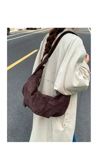 Detail of a large chocolate brown suede hobo bag worn with a chic beige trench coat