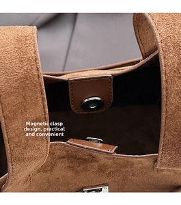 Detailed close-up of the magnetic buckle closure on a brown suede crossbody bucket bag
