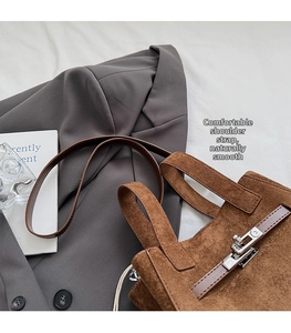 Close-up of brown suede bucket bag featuring silver twist lock and smooth leather straps