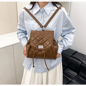 Detail of a brown quilted backpack featuring a silver twist lock and drawstring accents