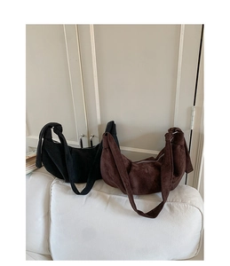 Detail of black and coffee suede hobo bags with knotted straps on a white sofa