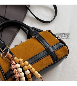 Detail of Boston bag with brown suede texture and wooden beaded tassel accessory
