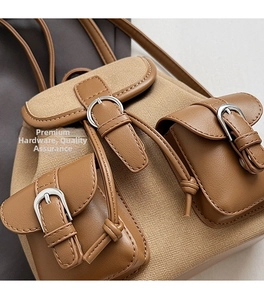 Dettaglio dello zaino in tela kaki con finiture in pelle marrone e fibbie metalliche