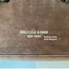 Close-up of matte brown suede texture with metallic logo and established date details