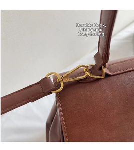 Close-up of golden metal hooks and fine stitching on a brown leather tote bag