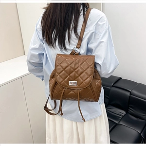 Detail of dark brown quilted leather backpack with metal turn-lock and drawstring closure