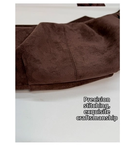Detailed macro view of precision stitching and dark brown suede material of the bag