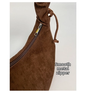 Makro-Detail des hochwertigen silbernen Metall-Reißverschlusses an der braunen Wildledertasche