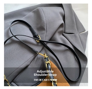 Macro view of adjustable black leather shoulder strap with gold-tone metal buckle and chain