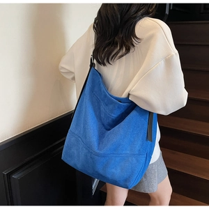 Détail du grand sac cabas bleu Klein avec texture en daim porté par un mannequin