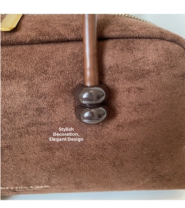Detail of dark brown matte suede shoulder bag featuring decorative spheres and golden zipper