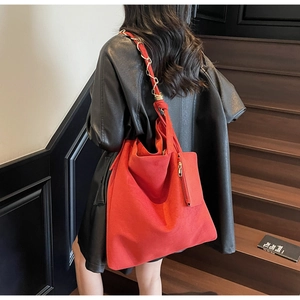 Détail d'un sac cabas rouge en daim avec chaîne dorée et petit porte-monnaie suspendu