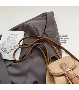 Dettaglio degli spallacci in pelle e fibbia argentata su uno zaino in tela beige