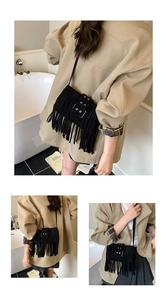 Détail d'un sac bandoulière en daim noir avec franges et boucle à œillets métalliques