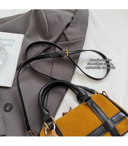 Detail of mustard yellow suede Boston bag with black leather straps and gold hardware