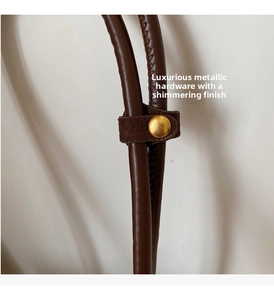 Detail of premium brown suede shoulder bag with polished gold metal hardware buckle
