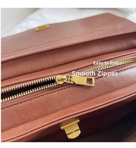 Detailed macro view of smooth golden metal zipper and grain leather texture on tote bag
