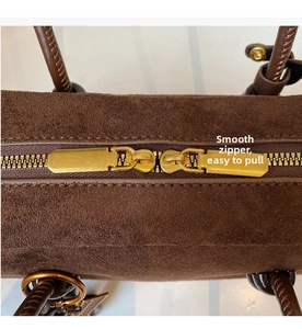Detail of smooth gold two-way zipper and brown suede texture on a vintage hobo bag