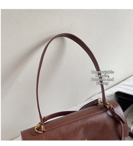 Detail view of the brown leather tote bag handle with golden metal rings and fine stitching