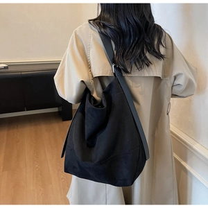 Detail of a large black matte crossbody tote bag with adjustable wide strap on model