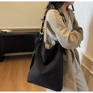 Détail du sac hobo en daim noir avec bandoulière entrelacée de chaînes métalliques et cuir