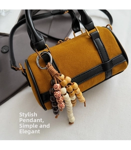 Close-up of vintage suede boston bag featuring ethnic beaded charm and leather straps