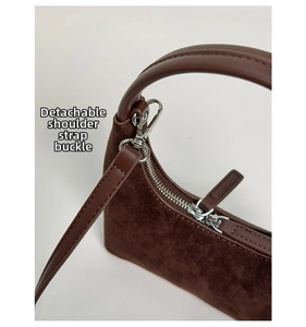 Detail of silver hardware and detachable strap on dark brown suede crescent bag