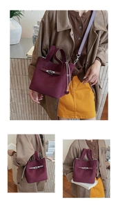 Detail view of burgundy suede bucket bag with silver lock and detachable strap