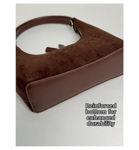 Close-up of the reinforced base and fine stitching on a dark brown suede handbag