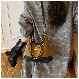 Detail of quilted brown suede shoulder bag with gold chain and twist lock on model