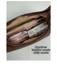 Spacious interior of brown suede shoulder bag with zipper closure and daily essentials