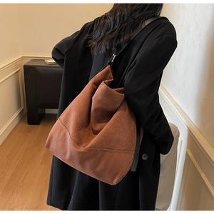 Brown suede tote bag with black wide strap showing natural drape and slouchy silhouette
