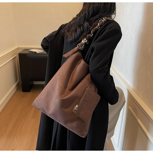 Détail du cabas en daim avec bandoulière en chaîne et petit porte-monnaie sur un mannequin