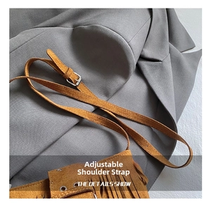 Détail de la bandoulière réglable avec boucle en métal argenté sur un sac à franges marron