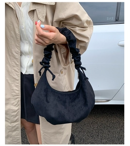 Nahaufnahme einer schwarzen Wildleder-Monadtasche mit gerafftem Griff und Kordelzug-Detail