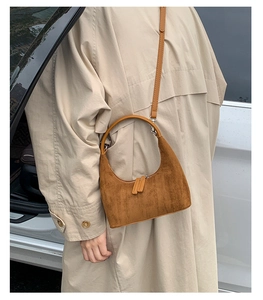 Brown suede half-moon shoulder bag styled with a classic beige trench coat for autumn
