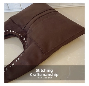 Détail du sac en daim marron foncé avec rivets argentés et finitions de couture fines