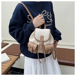 Dettaglio laterale di un mini zaino vintage in tela e pelle indossato dalla modella