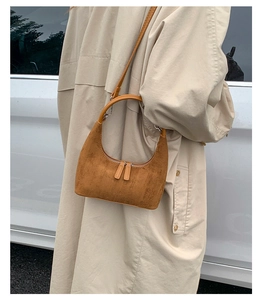 Side view of brown suede crescent bag with zipper fringe and shoulder strap details