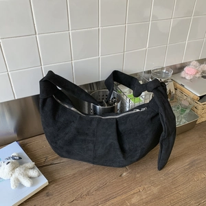 Detail of minimalist black suede hobo bag with knotted strap and silver zipper closure