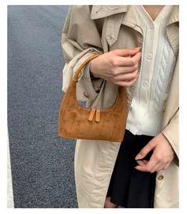 Detailed view of a brown suede hobo bag with a minimalist crescent shape and sleek zipper