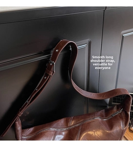 Detail of brown leather bag showing vintage texture, stitching, and adjustable shoulder strap