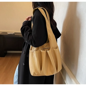 Detail of warm yellow large tote bag showing functional outer pockets and soft texture